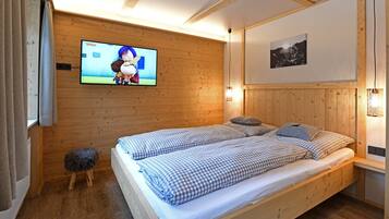 Een slaapkamer met houten lambrisering, een bed, een televisie en een aan de muur bevestigd schilderij.