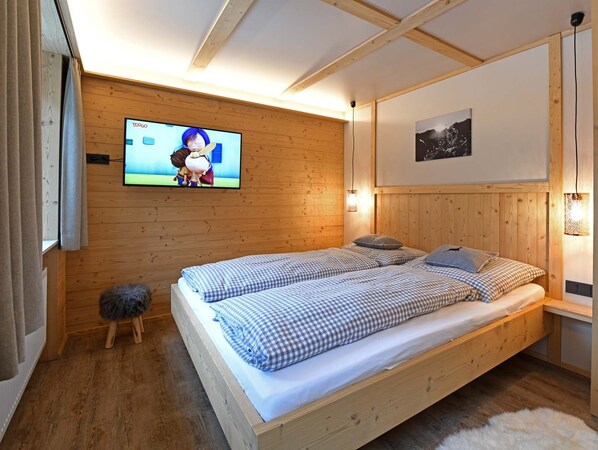 Ett sovrum med träpanel på väggarna, en säng, en tv och en tavla som hänger på väggen.