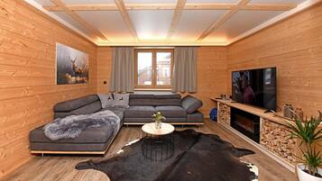 Een modern houten blokhutinterieur met een hoekbank, een televisie en een groot raam.