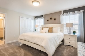 A bedroom with a large bed, bedside tables, a headboard, and a ceiling light. - Charming 4BR Home w/ Pool Mickey & Star Wars! (Kissimmee)