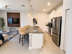A modern kitchen with a central island, stainless steel appliances, and a dining area with a sofa and chairs. - 4BR Storey Lake Home, Heated Pool (Kissimmee)