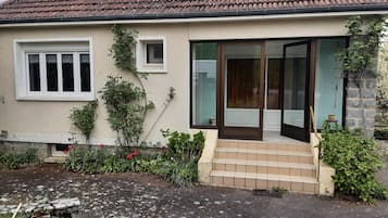 Een huis met een pannendak, een voordeur met ruitpanelen en een kleine tuin.