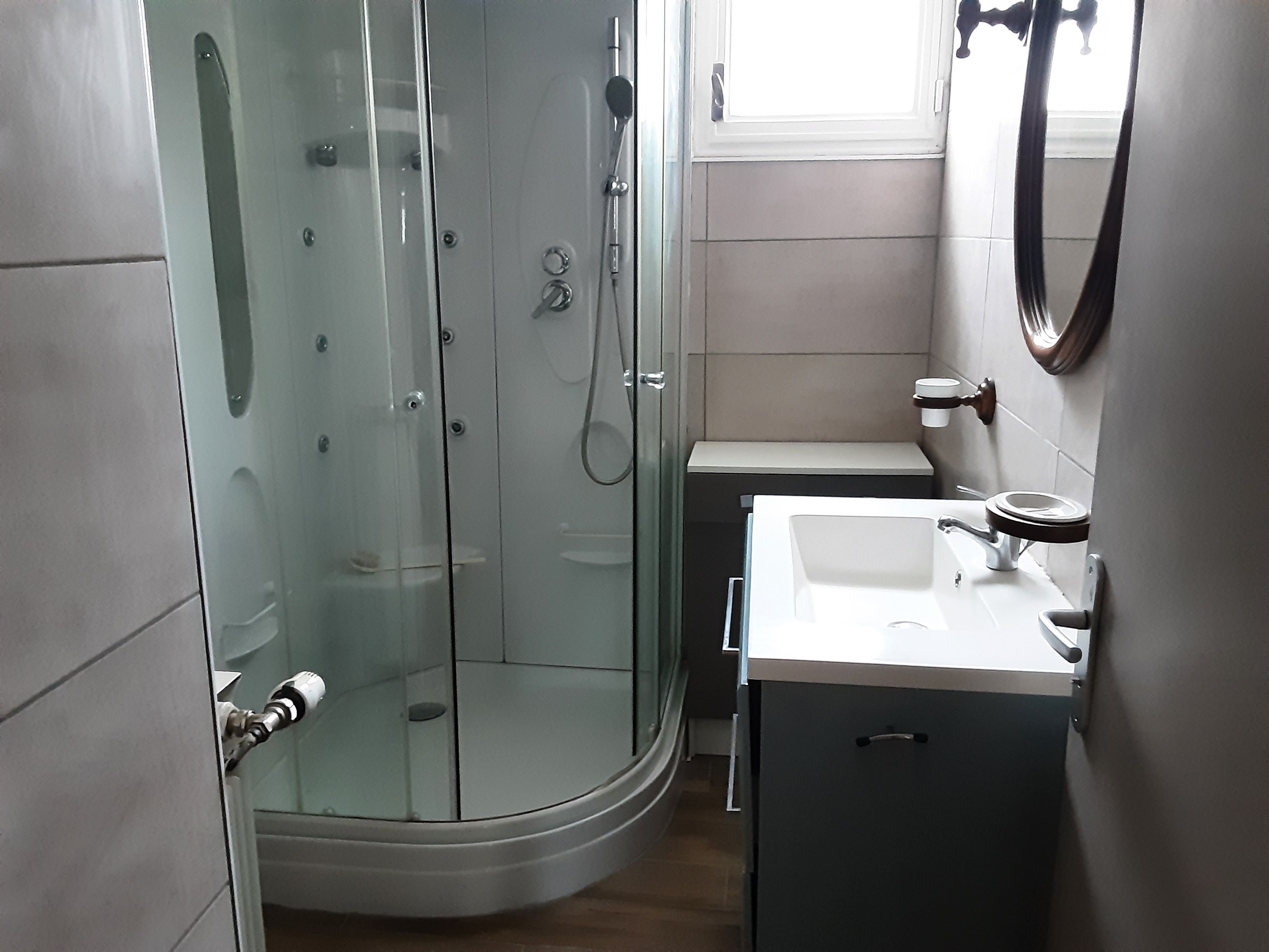 A bathroom with a glass-enclosed shower, a white sink, and a toilet.