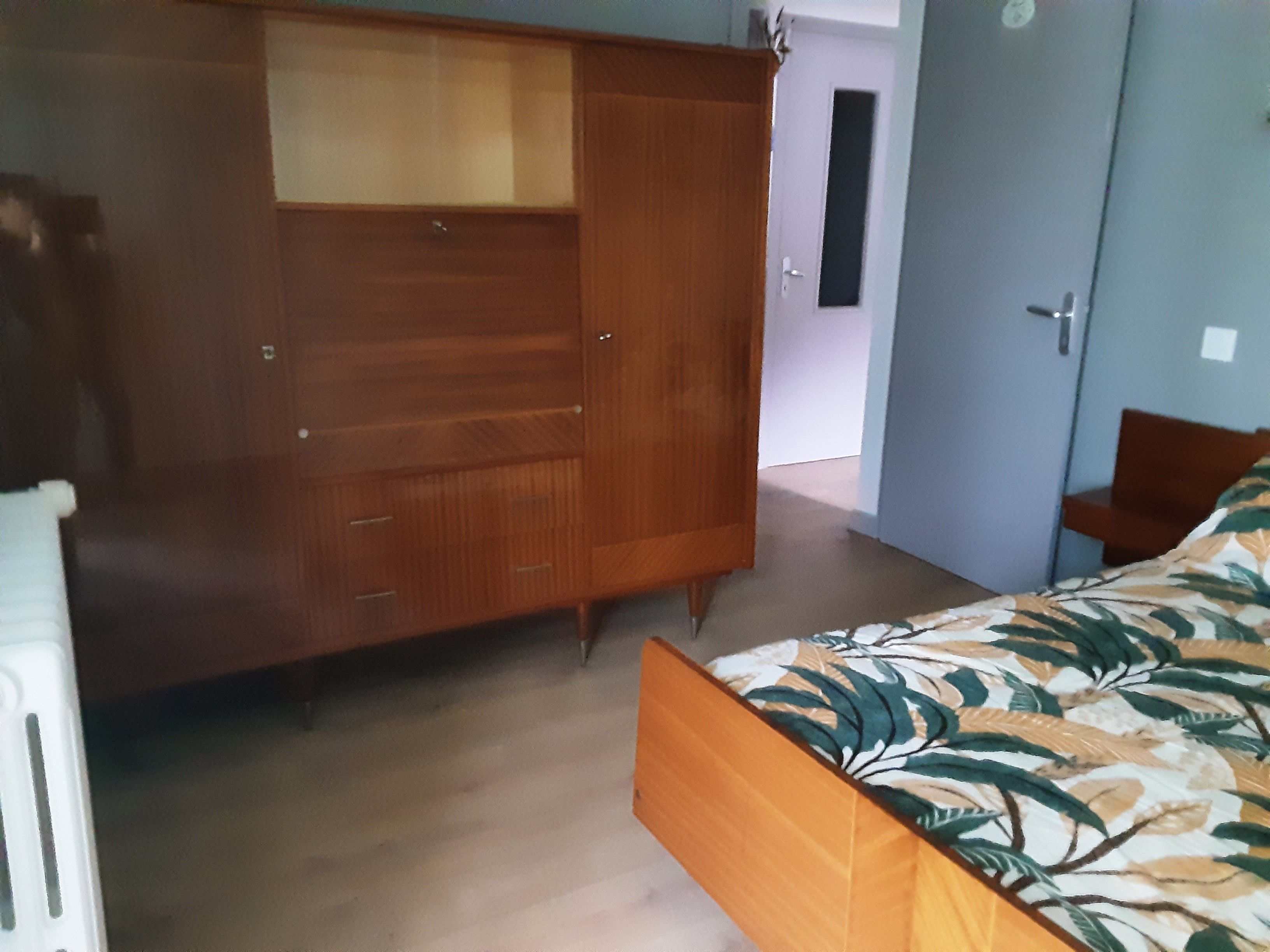 Een slaapkamer met een bed, een kledingkast en een deur naar een andere kamer.