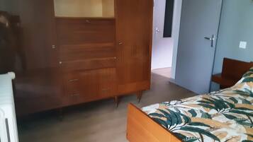 Een slaapkamer met een bed, een kledingkast en een deur naar een andere kamer.