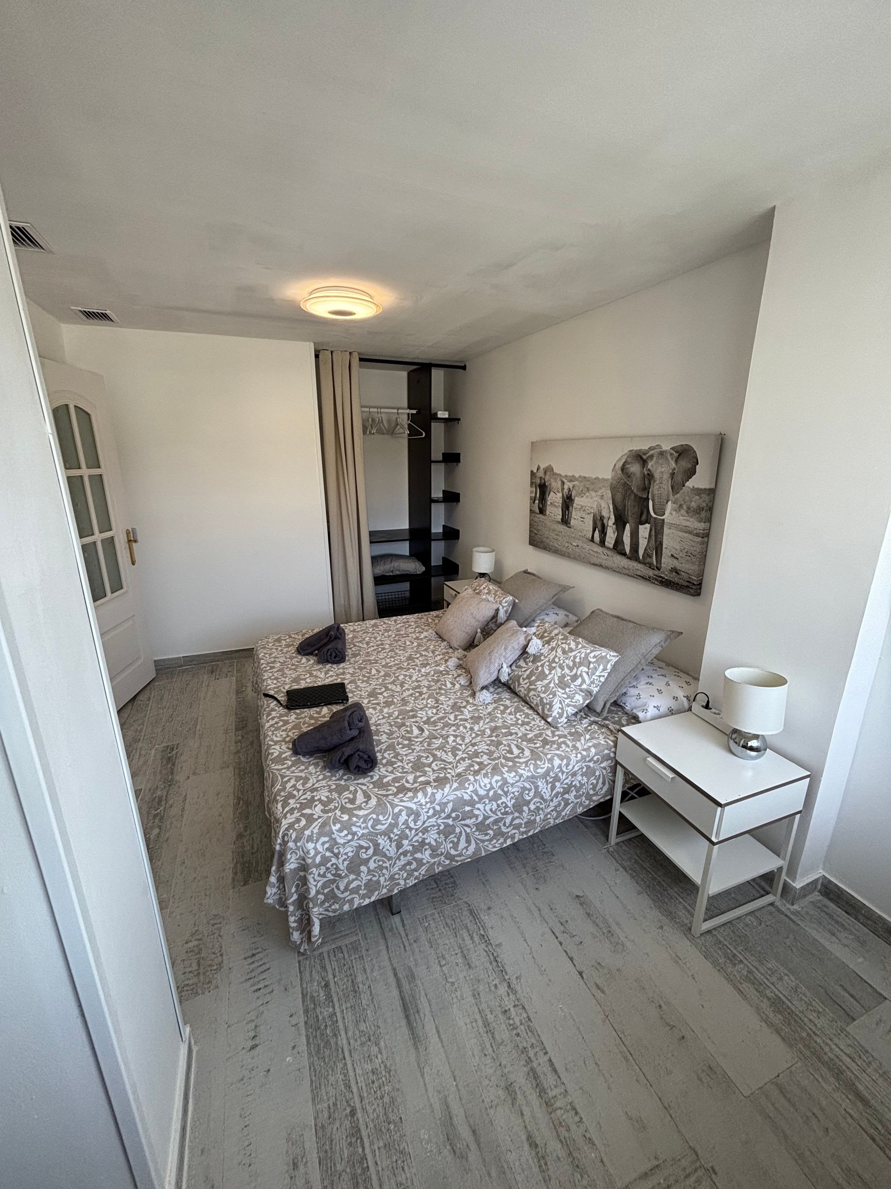 Ein Schlafzimmer mit Bett, Nachttisch und einem Wandbild.