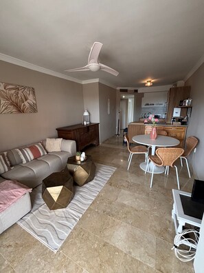 Ein modernes Wohnzimmer mit Sofa, Couchtisch und Essbereich mit Stühlen.