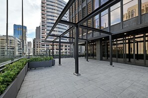 A modern urban rooftop terrace with a metal framework, potted plants, and a view of surrounding buildings. - Stylish 1-Bed Apartment Iconic High-Rise City Views (Cape Town)