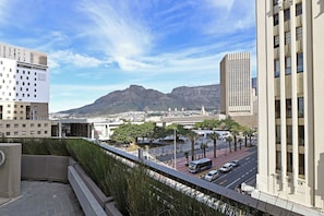 A cityscape with modern buildings, a clear sky, and a mountain in the distance. - Stylish 1-Bed Apart | Iconic High-Rise City Views (Cape Town)