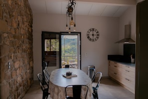 A dining area with a round table, chairs, a clock, and a view of the outdoors. - Holiday Home 'Gîte Chez Zephirin' with Mountain View, Shared Terrace and Wi-Fi (Fabras)
