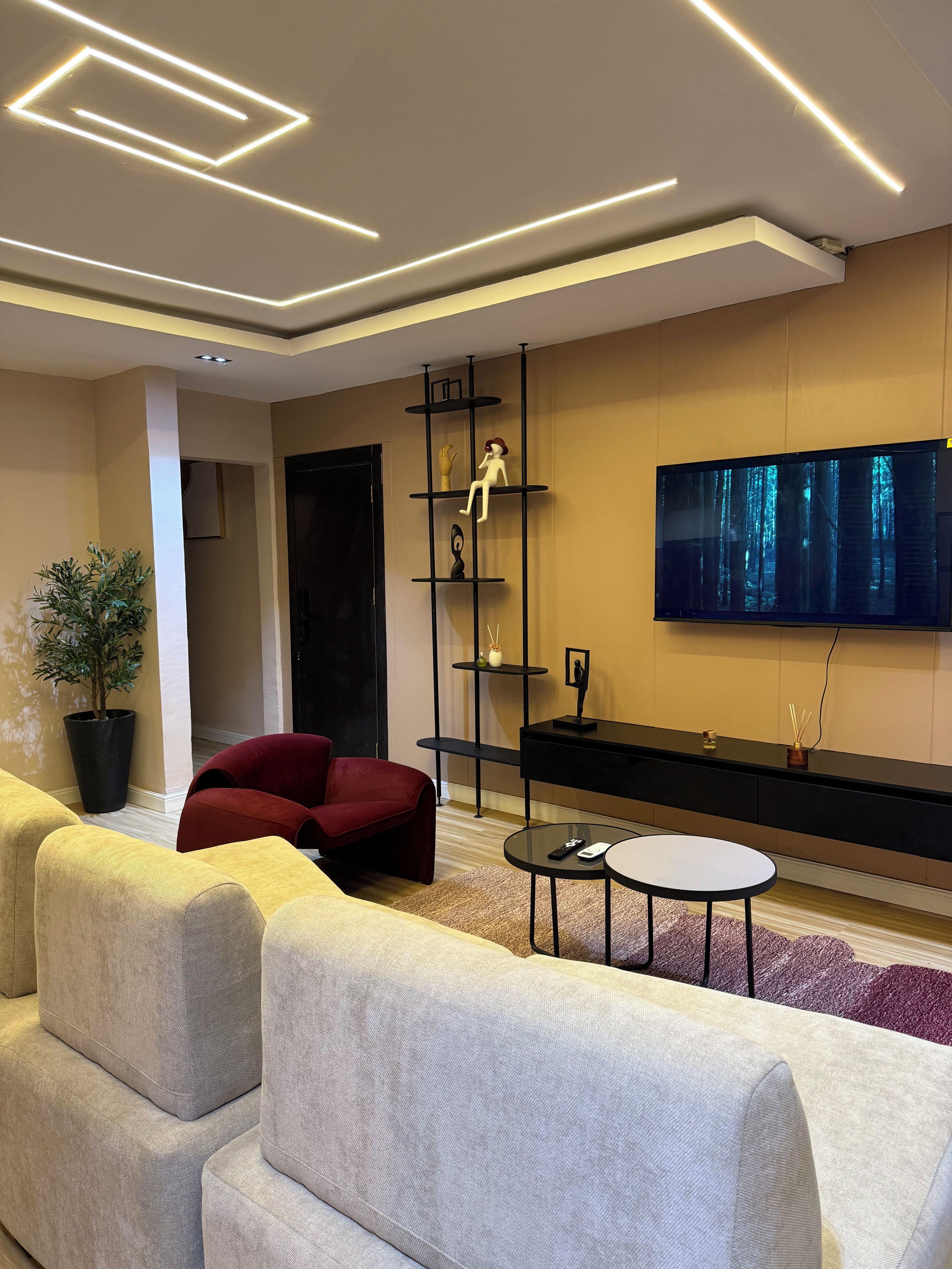 Ein modernes Wohnzimmer mit einer Couch, einem roten Sessel, einem Fernseher und einer schwarzen Unterhaltungsanlage.