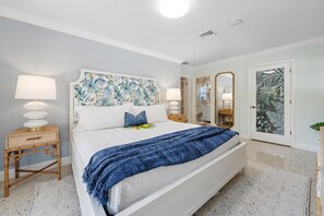 Een slaapkamer met een bed, nachtlampjes, een spiegel en een deur met een bladmotief.