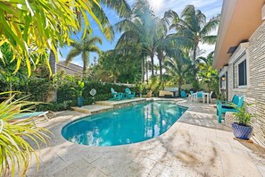 A swimming pool with lounge chairs, surrounded by palm trees and a stone patio. - The Coco Plum, Hot Tub, Island Living (West Palm Beach)