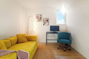 A modern living room with a yellow sofa, a blue armchair, a desk with a computer, and abstract art on the wall. - Spacious Modern House Rooftop Backyard Loft 3B2.5B (Seattle)