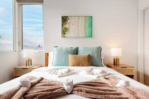 A hotel room with a bed, two bedside tables, a painting of a beach, and a window with a view. - Spacious Modern House Rooftop Backyard Loft 3B2.5B (Seattle)