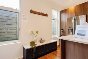 A modern kitchen with a stainless steel refrigerator, a wooden cabinet, and a white countertop. - Spacious Modern House Rooftop Backyard Loft 3B2.5B (Seattle)