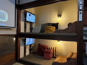 A bunk bed room with a television on the upper bunk, a wall-mounted light, and a remote control on the floor. - maicca2: A Traditional Japanese House in Numazu, Eura—Entire House Rental | Sleeps Up to 8 · BBQ · 100-inch TV · 1-minute walk to the marina (沼津市)