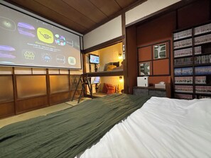 A room with a bed, a projector screen displaying content, a television, and a bookshelf. - maicca2: A Traditional Japanese House in Numazu, Eura—Entire House Rental | Sleeps Up to 8 · BBQ · 100-inch TV · 1-minute walk to the marina (沼津市)