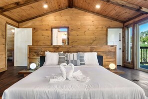 Ein Schlafzimmer mit Holzwänden, einem großen Bett, zwei Nachttischen und einem Spiegel über dem Bett.