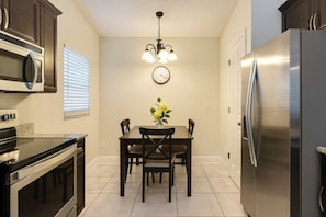 A kitchen with a dining table, chairs, a clock, a chandelier, a refrigerator, and an oven. - Private Pool Villa, 10 Mins to Disney&attractions! (Kissimmee)