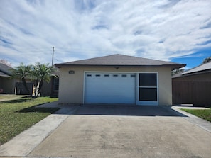 A single-story house with a garage, a small lawn, and a wooden fence. - Prime Location! Cozy Villa Near Disney & More (Kissimmee)