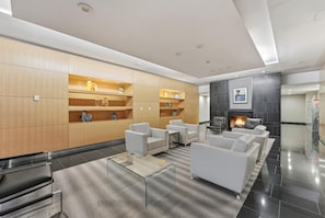 A modern lobby with a fireplace, seating area, and built-in shelving. - Toronto Views | 2BR | Raptors - Jays - CN Tower (Toronto)