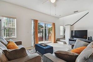 Een moderne woonkamer met een zithoek, een televisie en een trap naar een balkon.