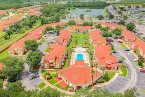 A residential area with houses having red roofs, a central swimming pool, and a lake in the background. - 3BR Lake Berkley Pool Home Near Disney (Kissimmee)