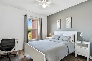 A bedroom with a bed, bedside tables, a desk, and a chair. - 3BR Lake Berkley Pool Home Near Disney (Kissimmee)