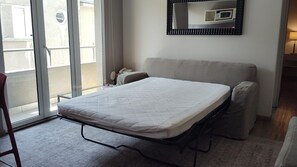 Ein Zimmer mit einem Bett, einem Sessel, einer Couch, einer Mikrowelle und einer Schiebetür.