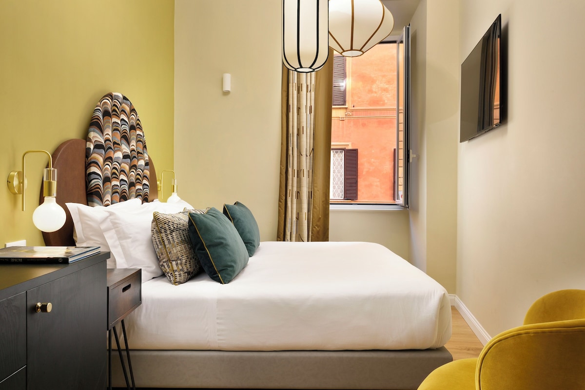 Een keurig opgemaakte slaapkamer met een bed, nachtkastje, lamp en een raam met gordijnen.