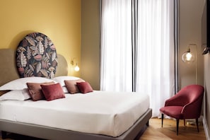 Een hotelkamer met een bed, een rode stoel, een ronde wanddecoratie en een wandlamp.