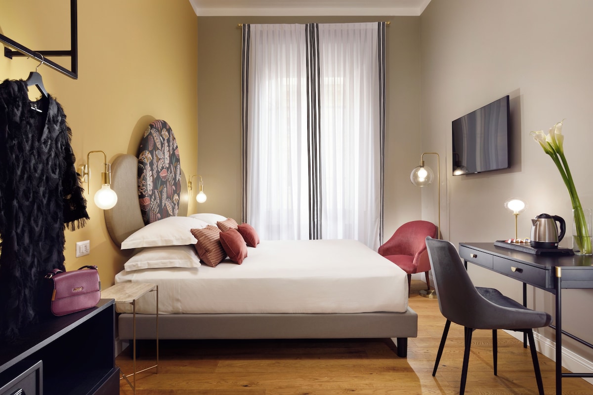Een moderne slaapkamer met een bed, nachtlampjes, een bureau en een stoel.