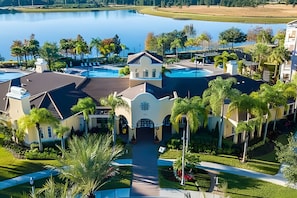 Un grand hôtel moderne doté de plusieurs piscines, entouré d’une végétation luxuriante et bordé d’un vaste lac.