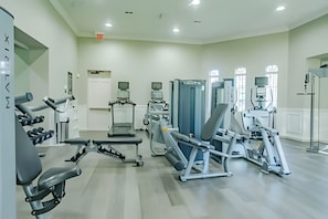 Une salle de sport équipée de divers appareils d’exercice, d’un tapis de course et d’un banc de musculation.