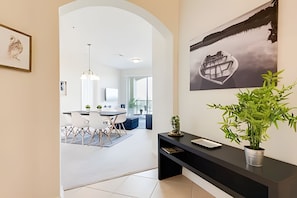 Un intérieur moderne comprenant un coin repas, une console noire agrémentée d’une plante et une œuvre d’art encadrée accrochée au mur.