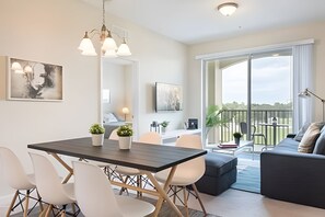 Un salon moderne avec un coin repas, de grandes fenêtres et un balcon.