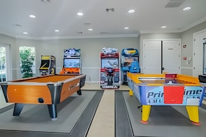 A pool table, a foosball table, and arcade machines in a room with white walls and a door in the background. - Vista Cay 3BR Condo Near Universal & Occc (Orlando)