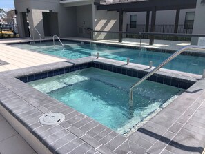 A rooftop pool with clear blue water, surrounded by a tiled deck and a covered area with a railing. - 3BR Terra Esmeralda Townhome, Free BBQ (Kissimmee)
