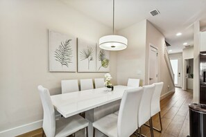 A modern dining area with a white table and chairs, a pendant light, and wall art. - Hf-17528 - 4br/3ba Modern Home Private Pool (Clermont)