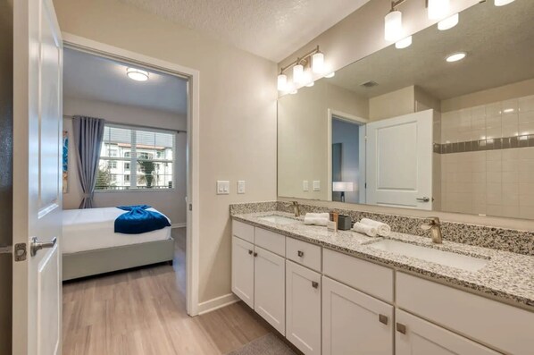 A hotel bathroom with a large mirror, a sink, and a shower area. - Vista Cay Comfort 3BR Resort Condo & Pool (Orlando)