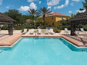 A clear blue pool with lounge chairs and a pergola, surrounded by a tiled patio and a yellow building in the background. - 4BR Bella Vida Lakeview Pool Townhome (Kissimmee)