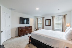 A bedroom with a large bed, a dresser, a television, and a window with curtains. - 4BR Bella Vida Lakeview Pool Townhome (Kissimmee)