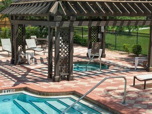 Un espace piscine agrémenté d’une pergola, de chaises longues et d’une petite piscine.