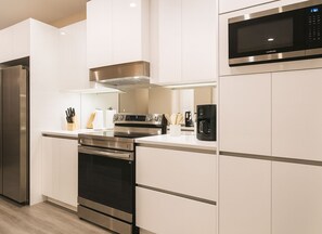 A modern kitchen with stainless steel appliances, white cabinetry, and a built-in microwave. - Modern 4 Suites Home Magic Village (Kissimmee)