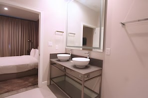 A modern bathroom with two white sinks, a large mirror, and a bed with a curtain. - Modern 4 Suites Home Magic Village (Kissimmee)