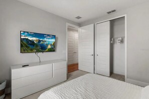 A bedroom with a bed, a TV mounted on a dresser, and a closet with sliding doors. - 3BR Reunion Townhome, 10 min to Disney (Kissimmee)
