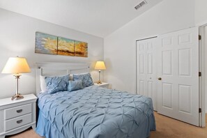 A bedroom with a bed, two bedside tables, a nightstand, a door, and a wall-mounted painting. - 4BR Home w/ Private Pool & Spa Near Disney (Kissimmee)