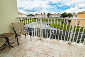 A balcony with a chair, a view of a water feature, and a row of houses in the background. - Lermont Townhome w/ Private Pool - Near Disney (Clermont)