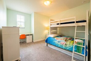A bunk bed with a colorful quilt, a desk with a chair, and a lamp. - Lermont Townhome w/ Private Pool - Near Disney (Clermont)